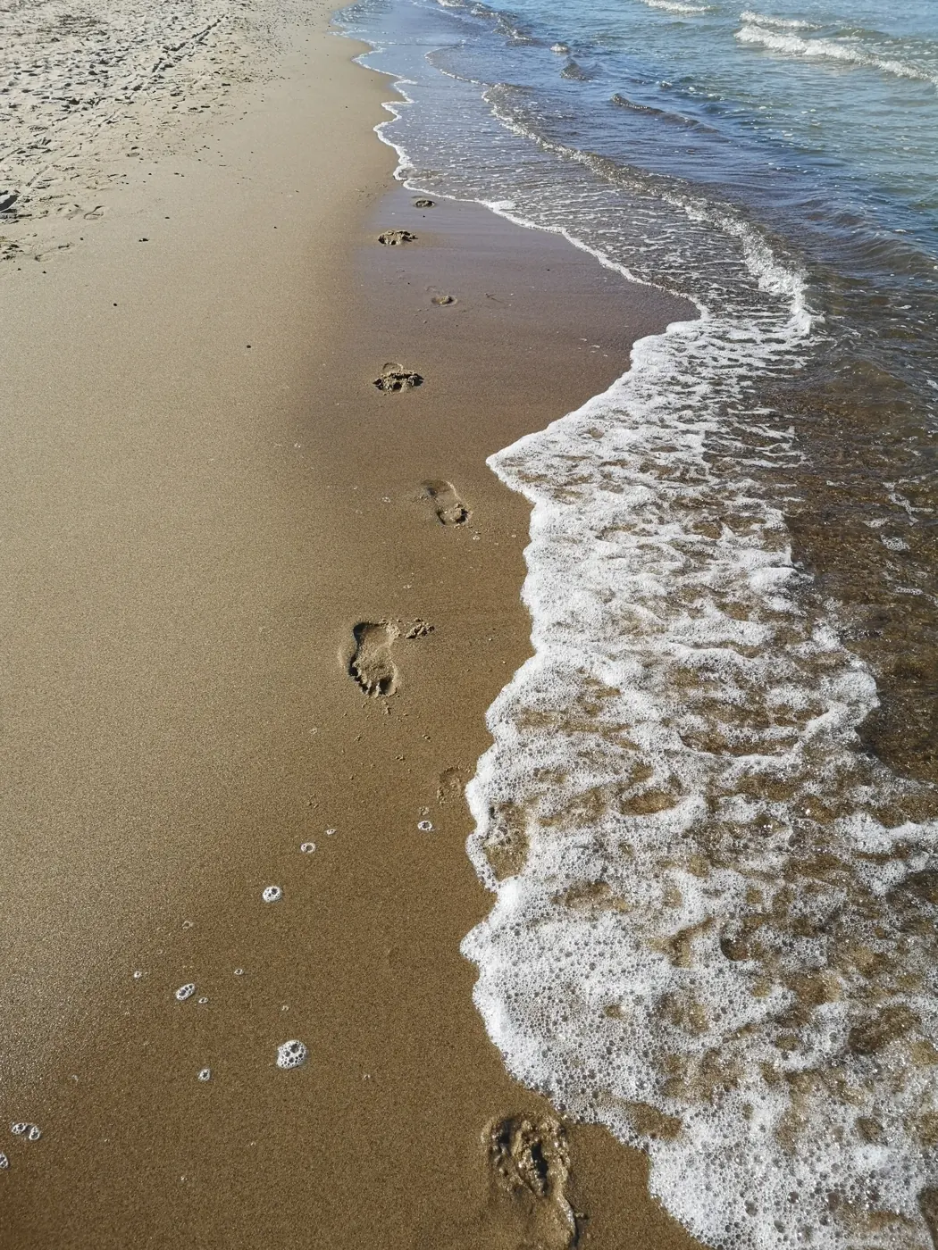 Meine Fußspuren am Meer, direkt neben der auslaufenden Brandung